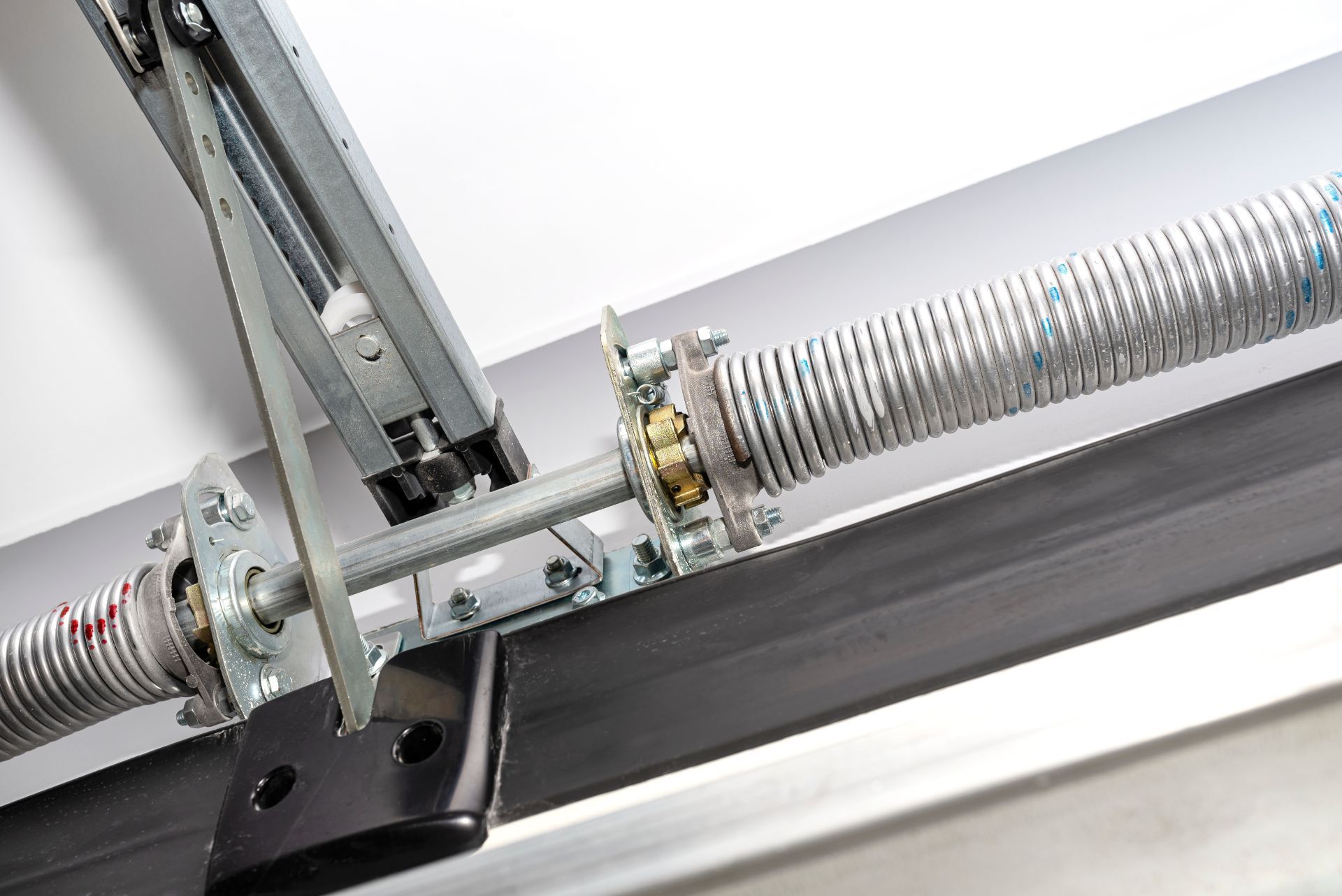 Garage door spring mechanism with coiled spring and metal hardware.