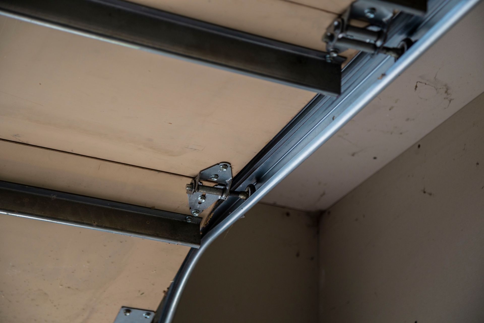 Garage door track and hardware, inside view. Metal tracks attached to ceiling and garage door panel.