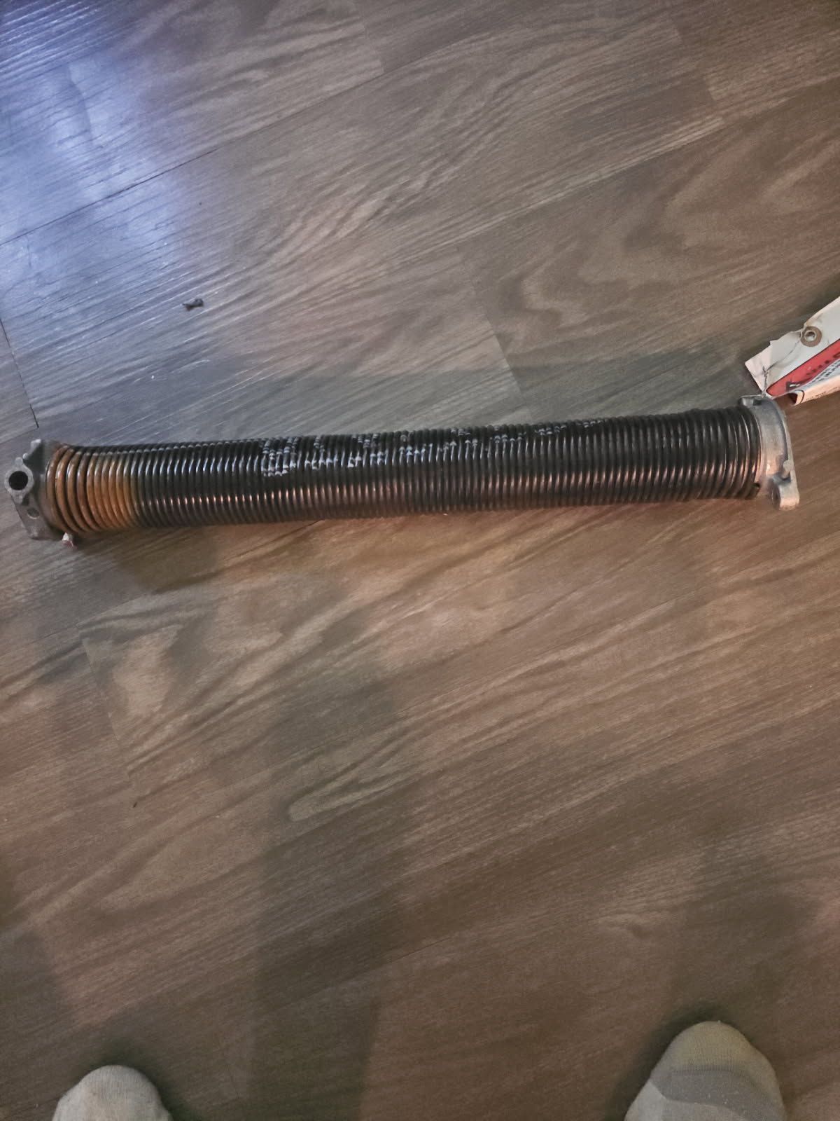 A broken garage door torsion spring on a wooden floor.