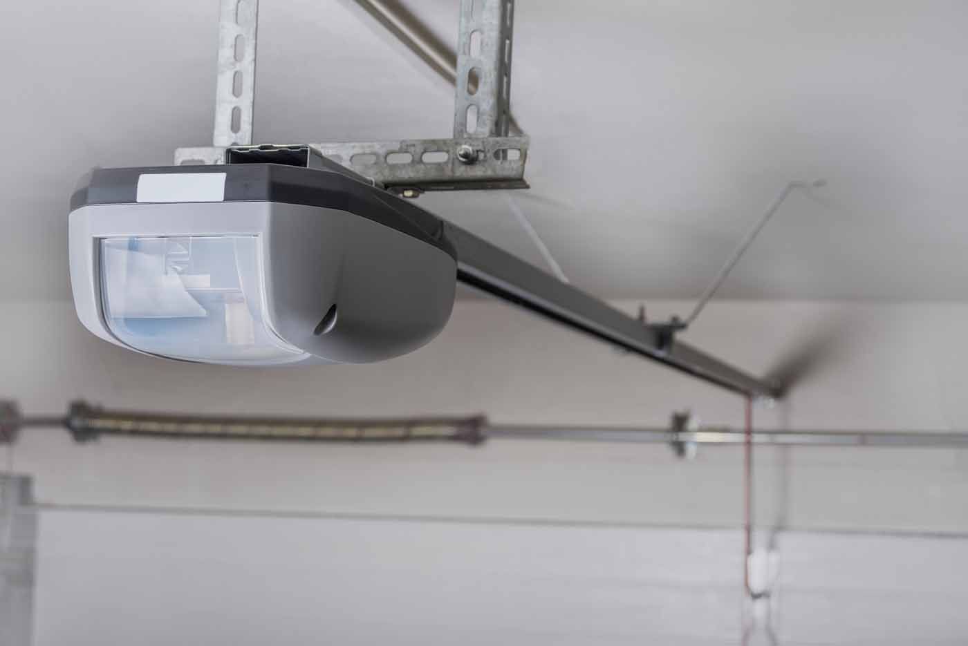 Garage door opener attached to ceiling, with a metal rail and coiled spring visible.