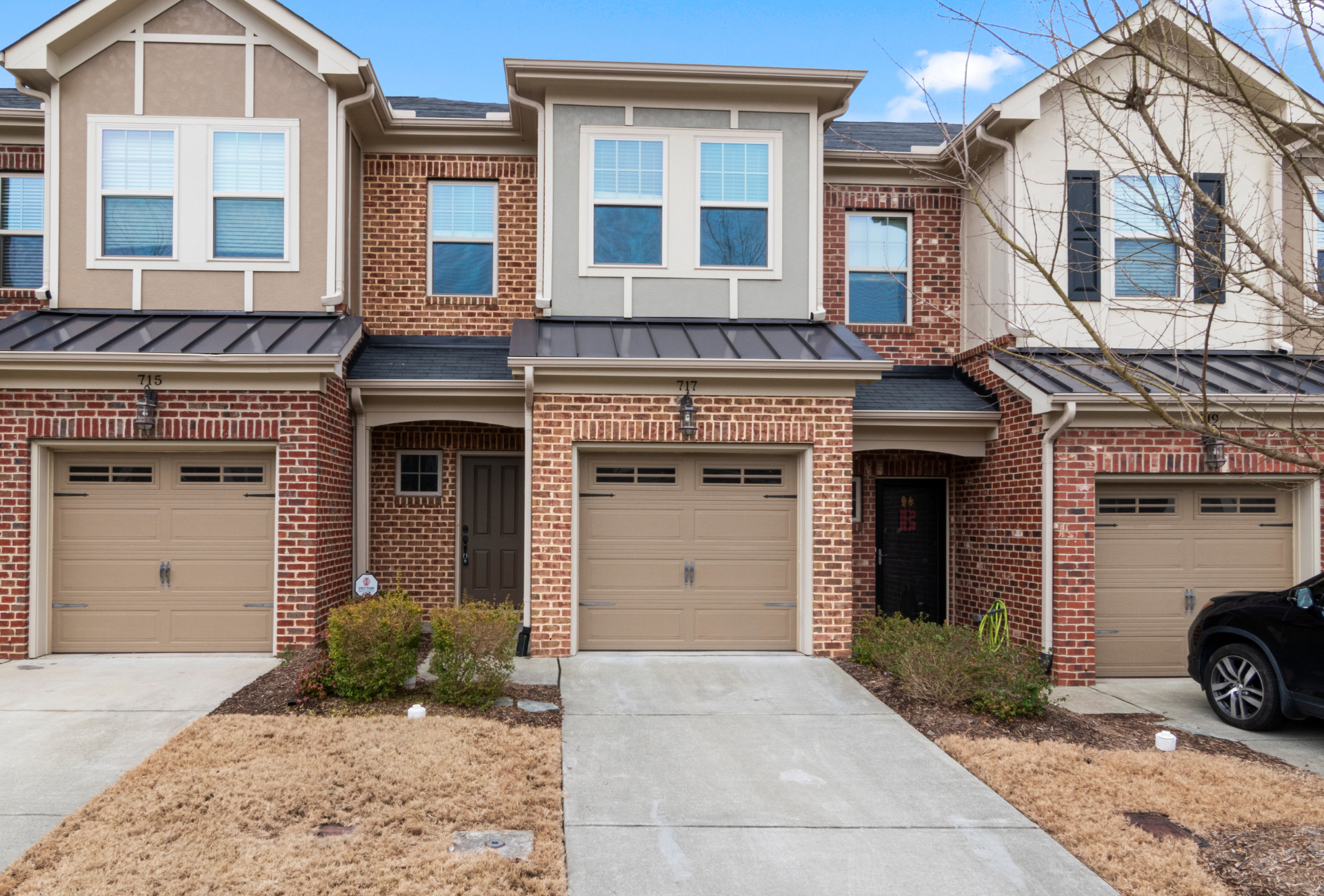 Townhomes with brick facades, tan garage doors, and concrete driveways.