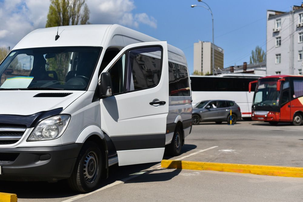 A White Van Is Parked in A Parking Lot Next to A Bus — G & D Ross Bus Charters In Brisbane, QLD