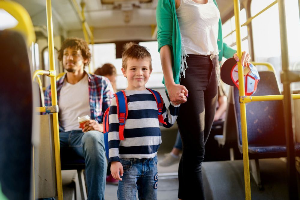 A Woman Is Holding a Child 's Hand on A Bus — G & D Ross Bus Charters In Magnolia, QLD