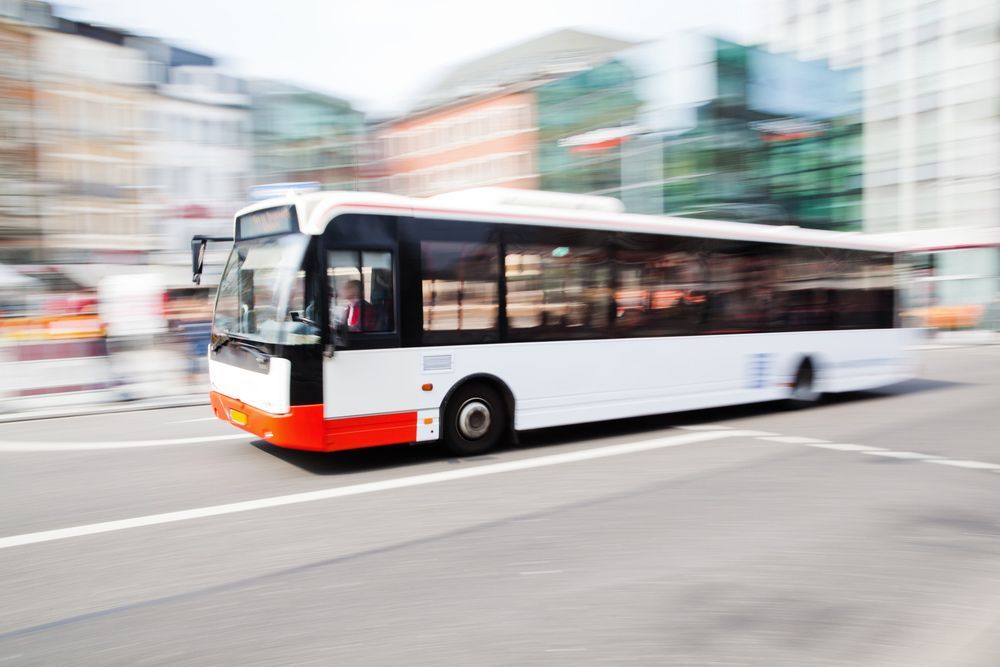 A White and Orange Bus Is Driving Down a City Street — G & D Ross Bus Charters In Toowoomba, QLD