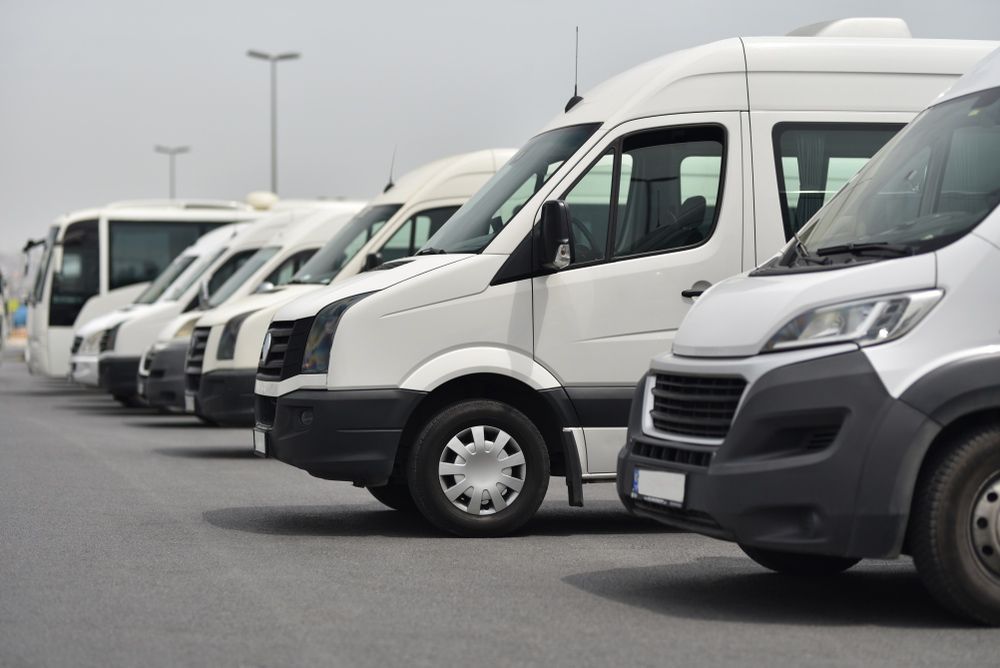 A Row of White Vans Are Parked in A Parking Lot — G & D Ross Bus Charters In Gladstone, QLD