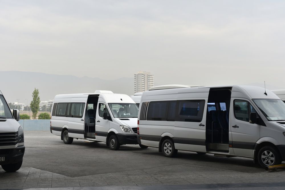 A Row of White Vans Are Parked in A Parking Lot — G & D Ross Bus Charters In Rockhampton, QLD