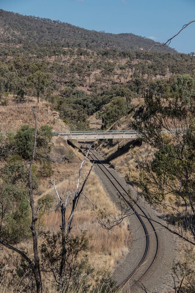 A bridge over a train track in the middle of a forest — G & D Ross Bus Charters In Magnolia, QLD