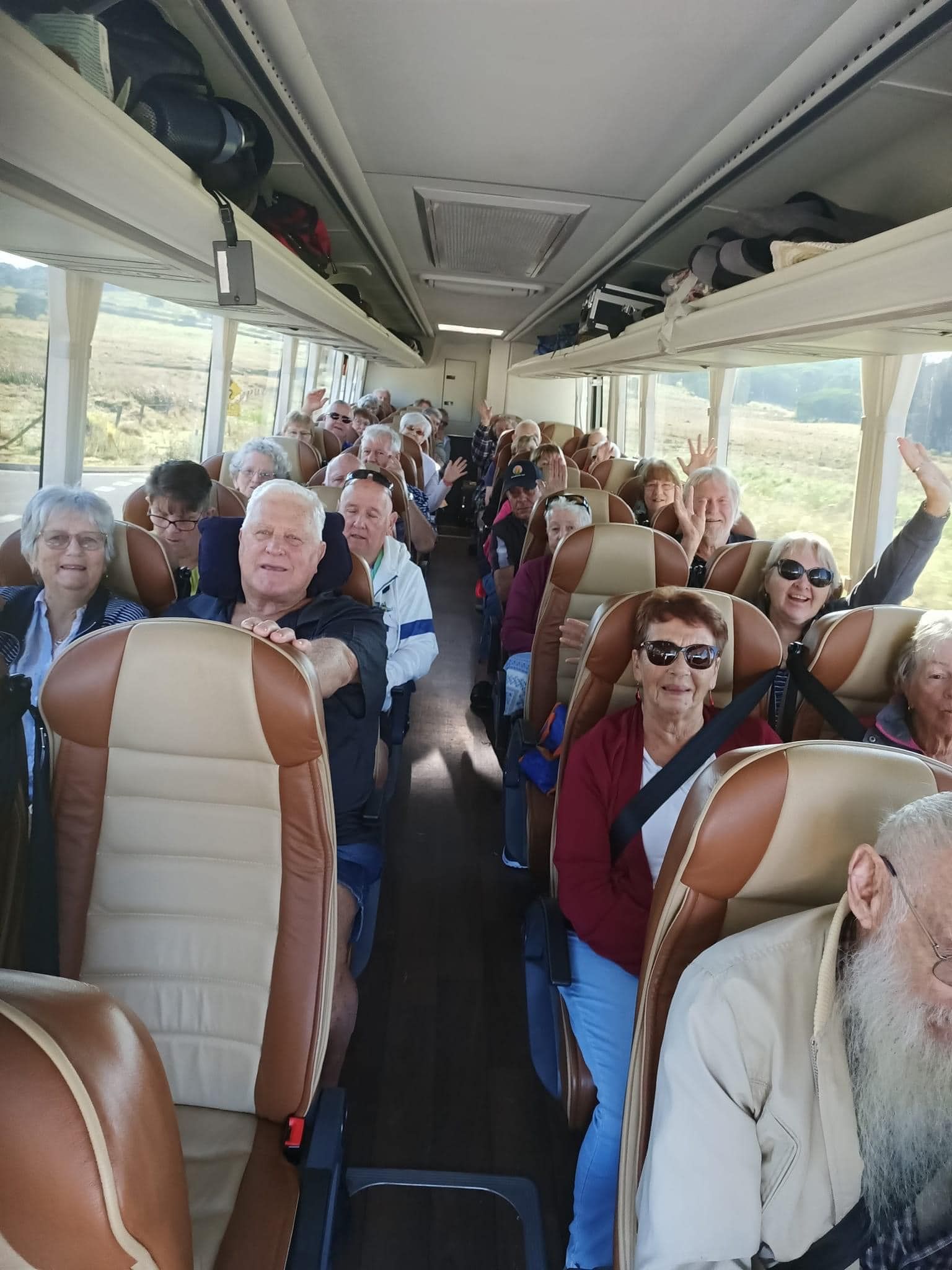 A Happy Group of People Are Sitting on A Bus — G & D Ross Bus Charters In Magnolia, QLD