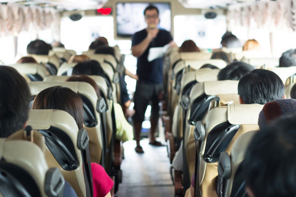 A Man Is Standing in Front of A Bus Full of People — G & D Ross Bus Charters In Rockhampton, QLD