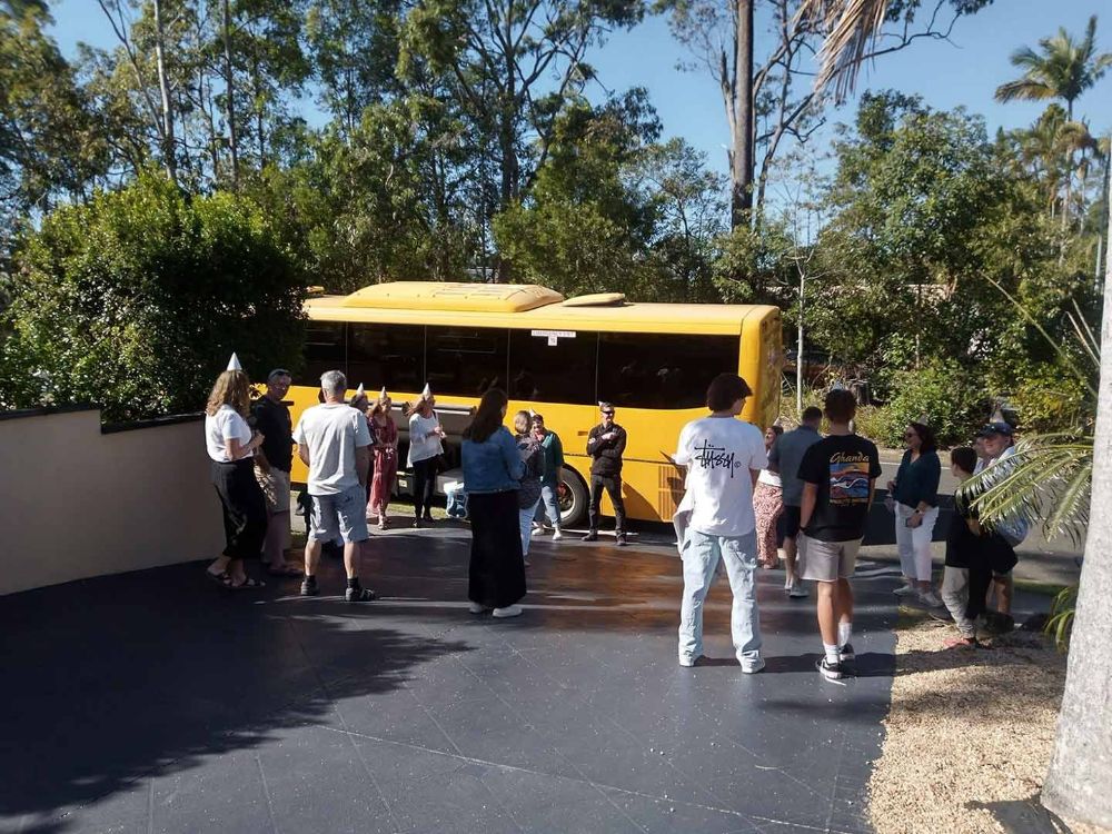 A Group of People Standing in Front of A Yellow Bus — G & D Ross Bus Charters In Maryborough, QLD