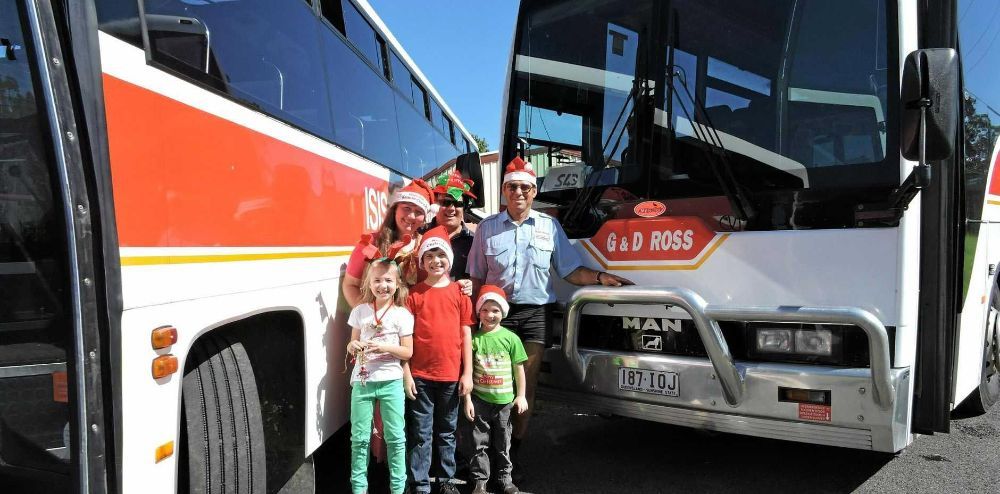 A Group of People Wearing Santa Hats Are Standing in Front of Two Buses — G & D Ross Bus Charters In Maleny, QLD