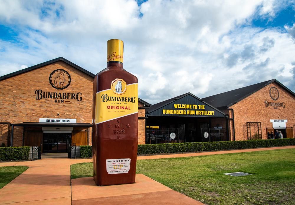A Large Bottle of Bundaberg Rum Is in Front of A Building — G & D Ross Bus Charters In Bundaberg, QLD
