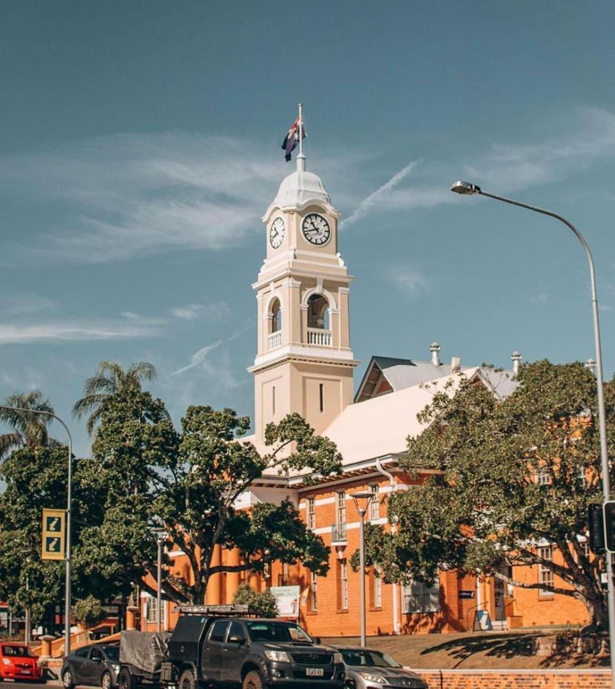 A Large Clock Tower with A Flag on Top of It — G & D Ross Bus Charters In Maryborough, QLD