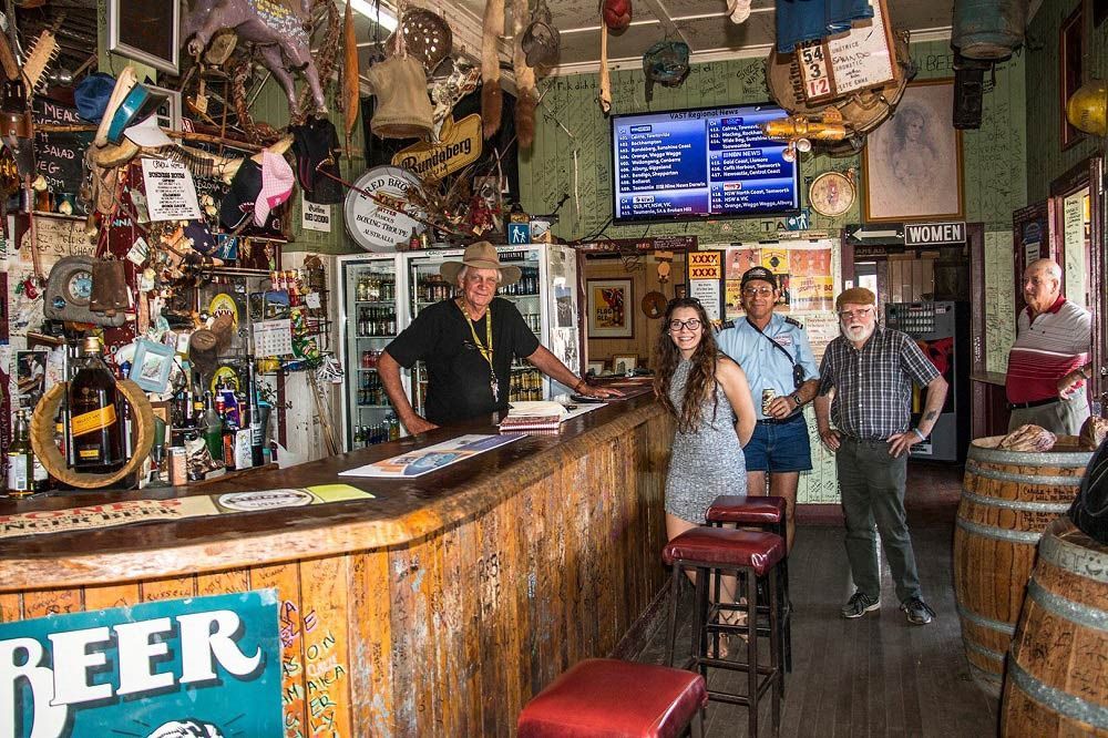A Group of People Standing in Front of A Bar with A Sign that Says Beer — G & D Ross Bus Charters In Gladstone, QLD
