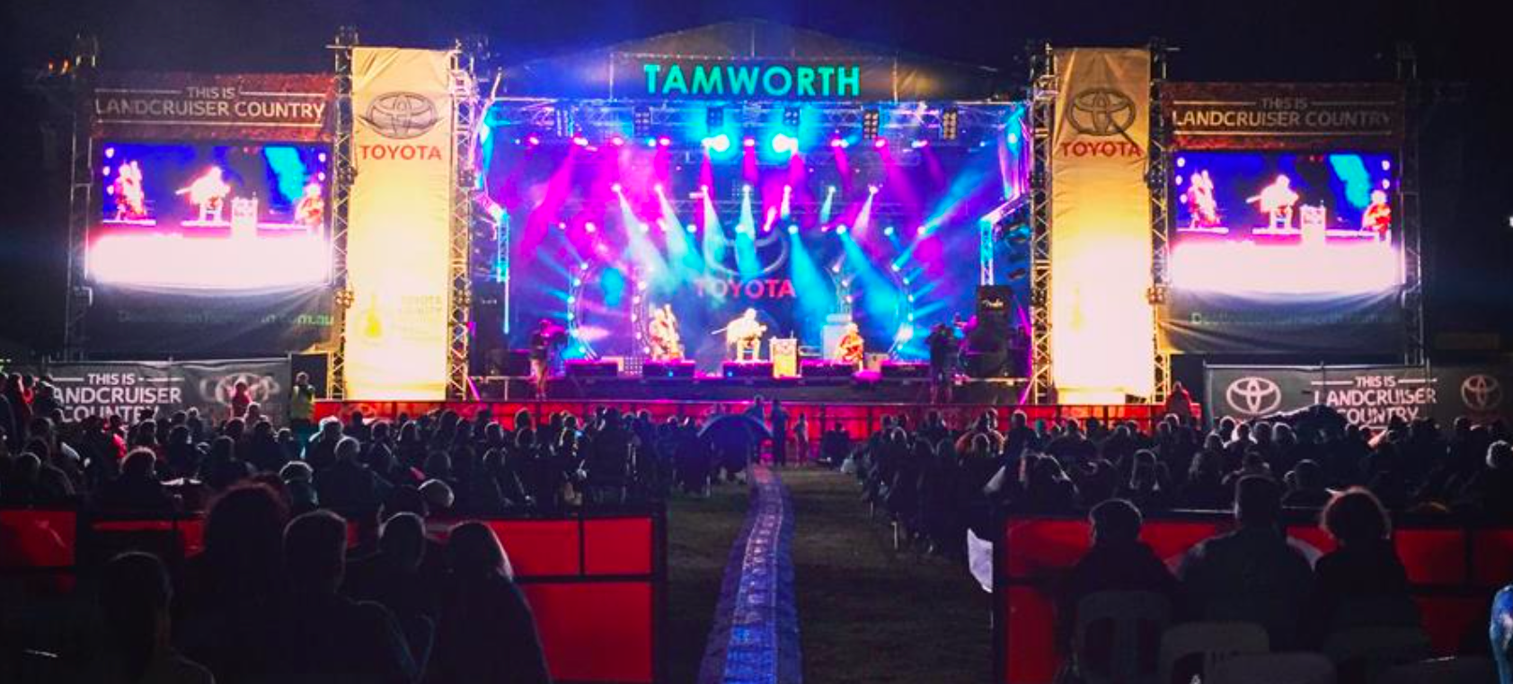 A crowd of people are sitting in front of a stage at a concert.