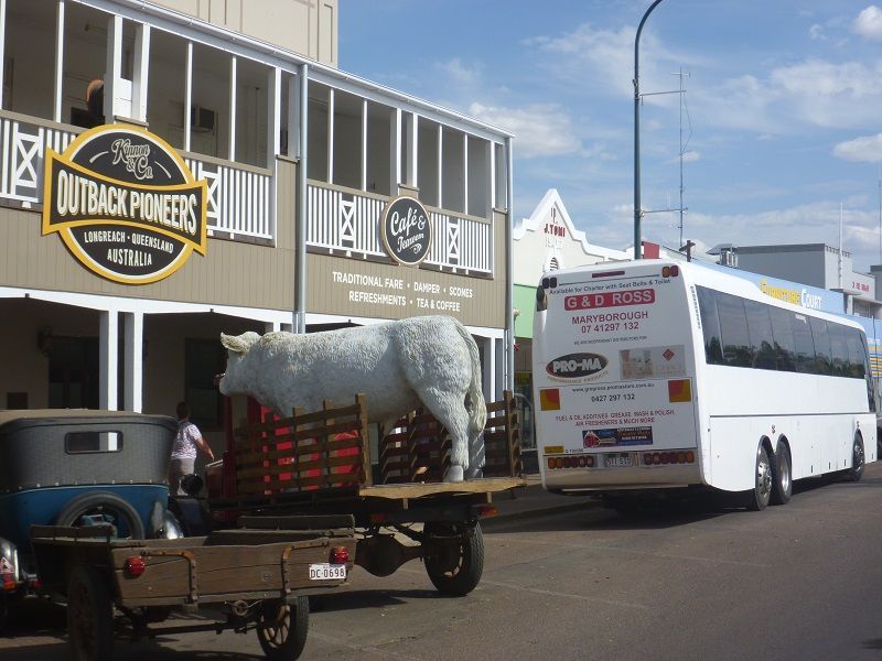 A White Bus Is Parked in Front of A Building that Says Outback Pioneers — G & D Ross Bus Charters In Magnolia, QLD
