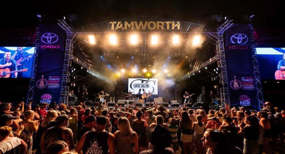 A Crowd of People Are Standing in Front of A Stage at A Concert — G & D Ross Bus Charters In Magnolia, QLD