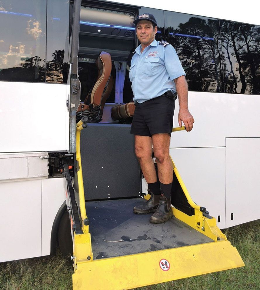 A Man Is Getting Off a Bus with A Handicap Ramp — G & D Ross Bus Charters In Magnolia, QLD