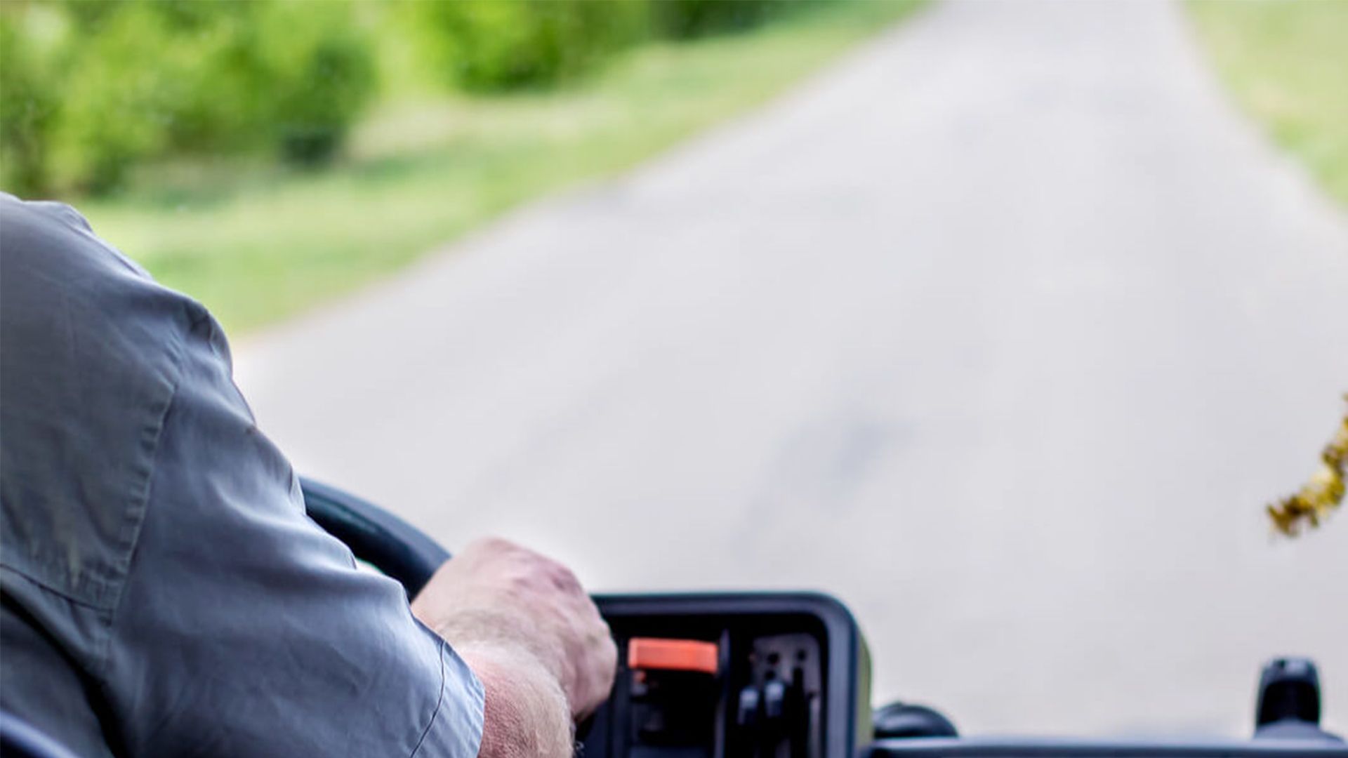 A Man Is Driving a Tractor Down a Road — G & D Ross Bus Charters In Magnolia, QLD