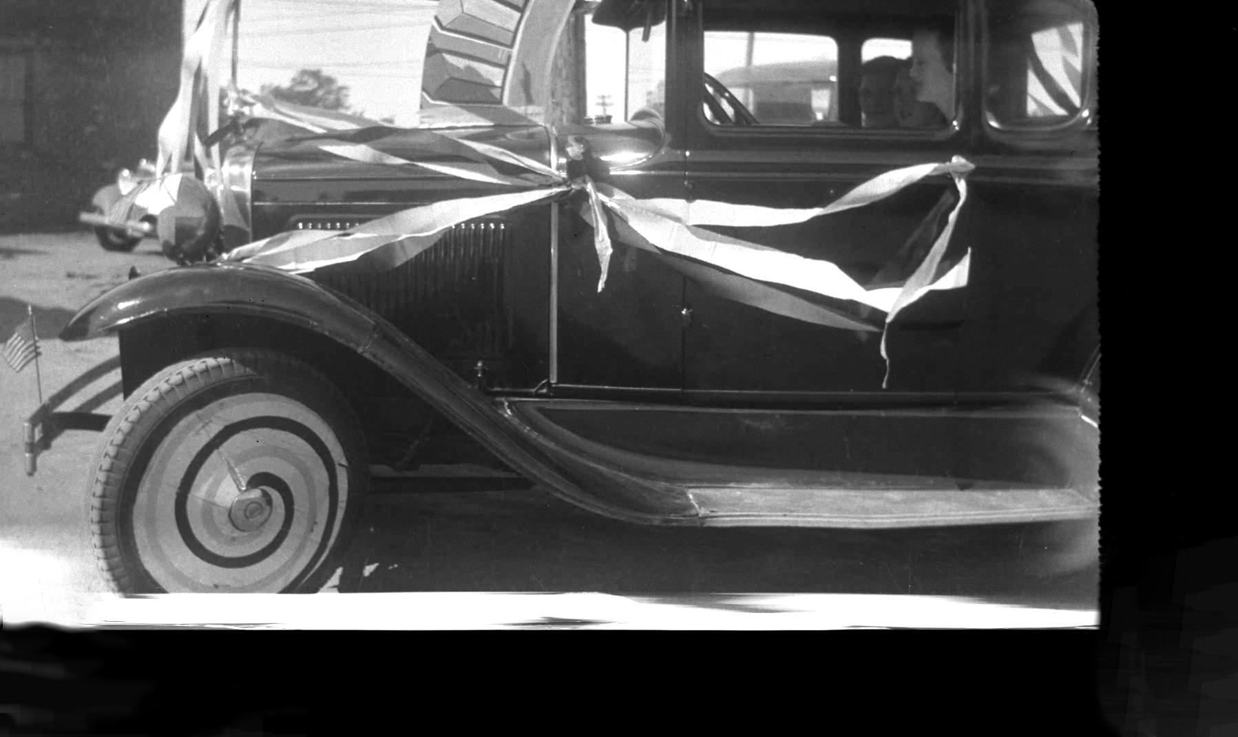 A black and white photo of an old car with a broken windshield