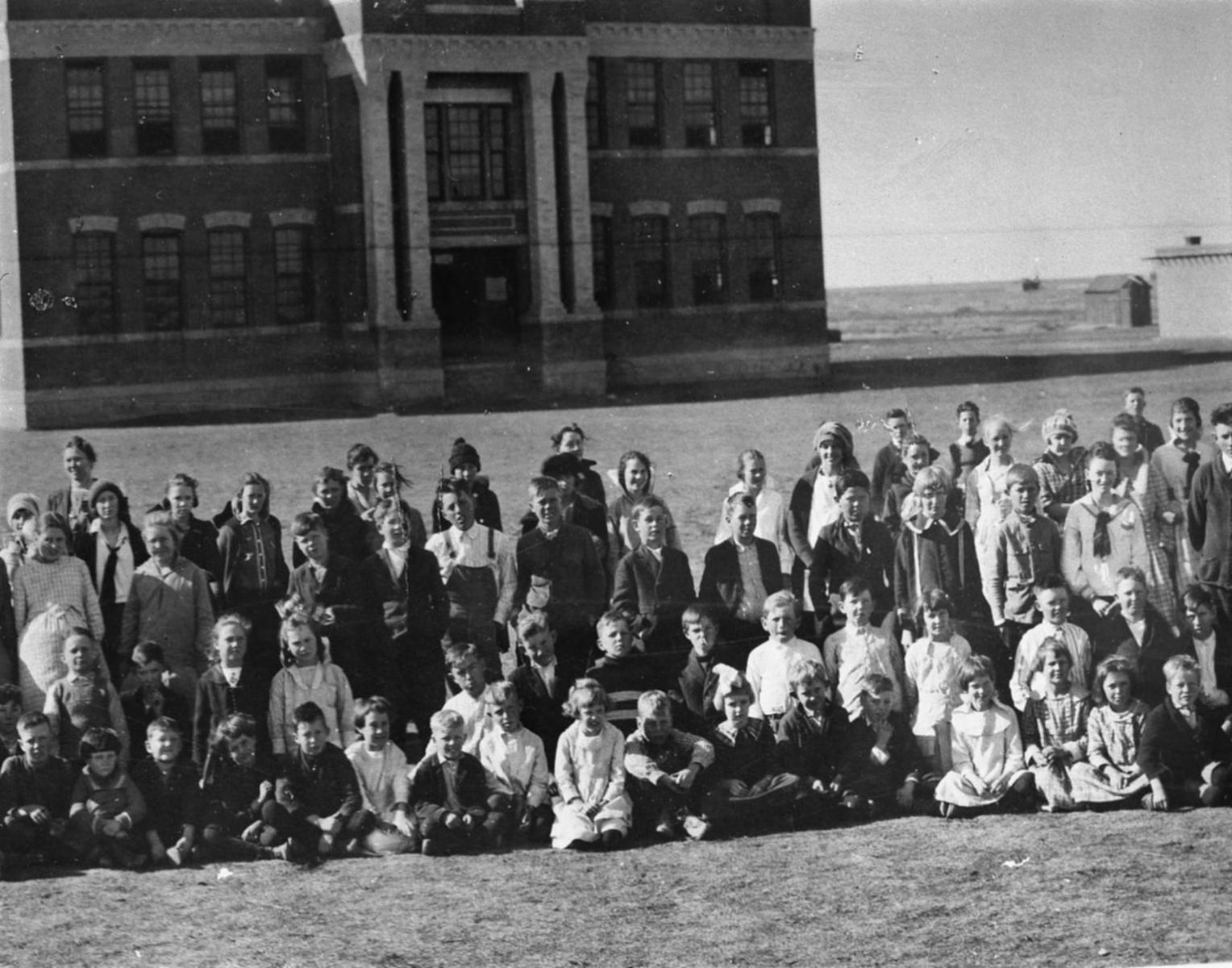 A large group of people are posing for a picture in front of a large building