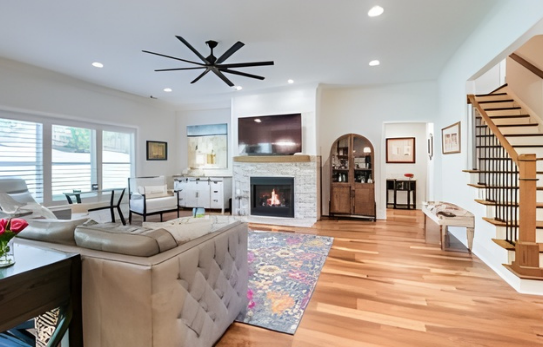 Dining room with wooden table, chairs, and a window with light gray curtains.
