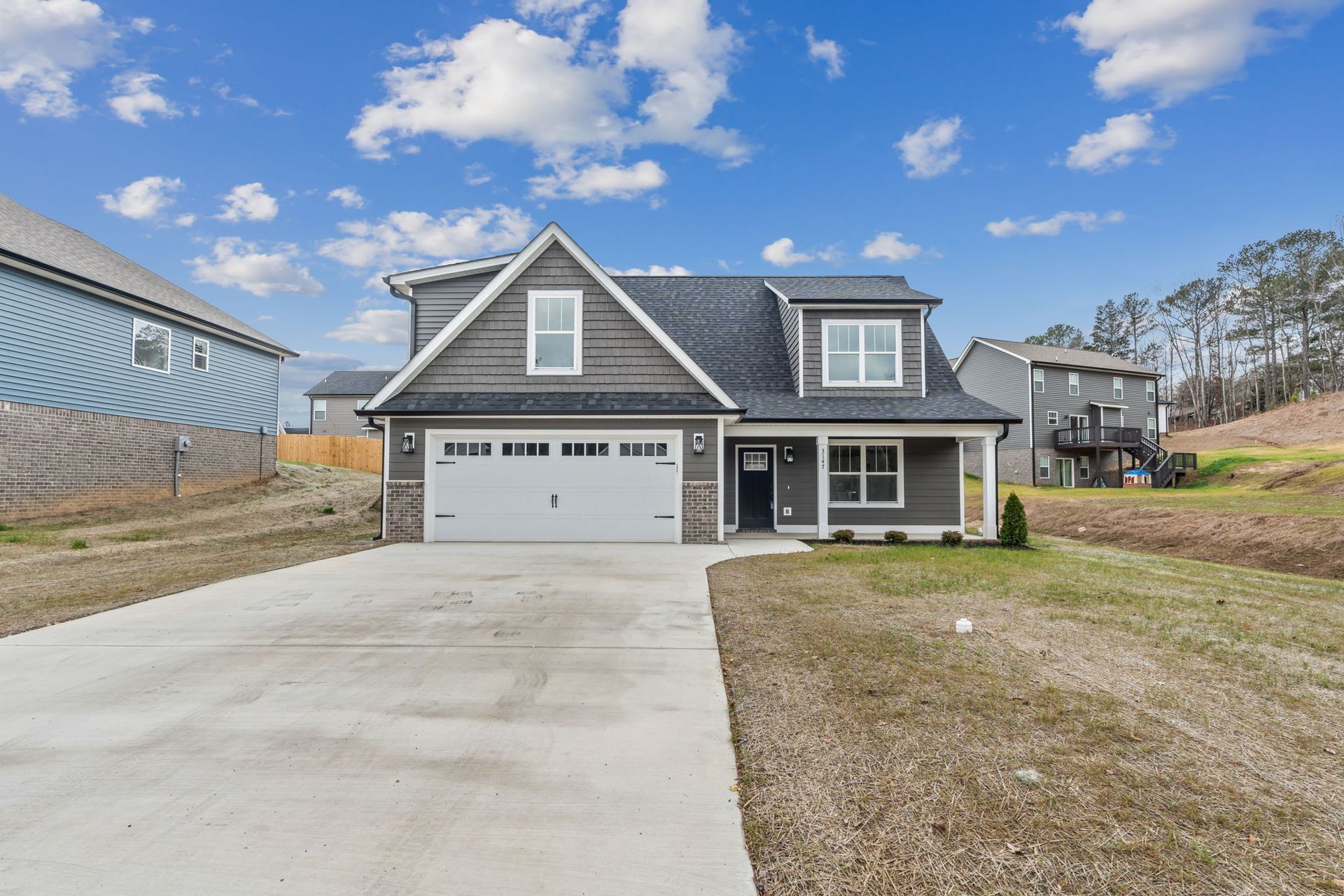 A large gray house with a white garage door is for sale.