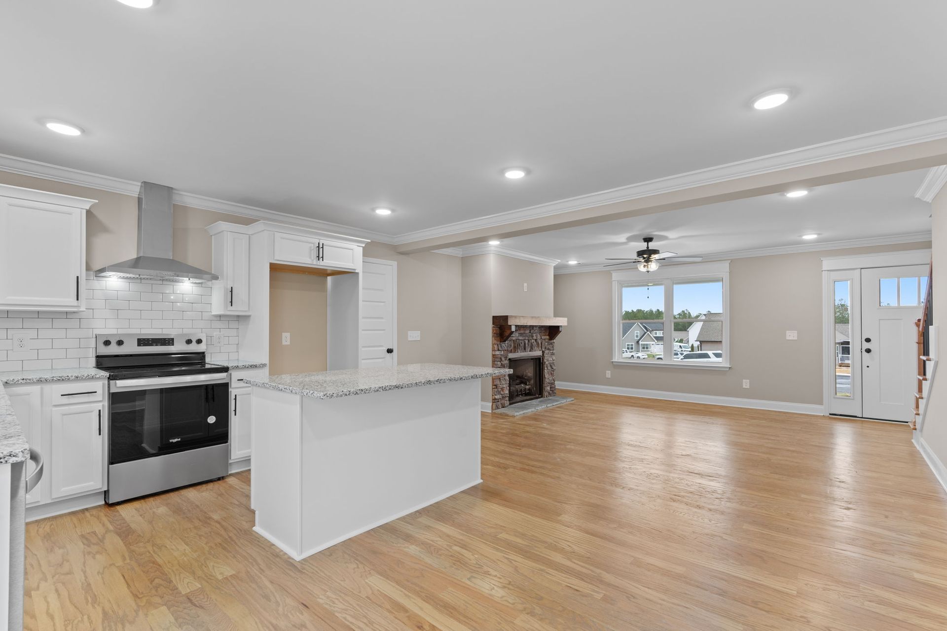 A kitchen with stainless steel appliances , white cabinets , hardwood floors and a large island.