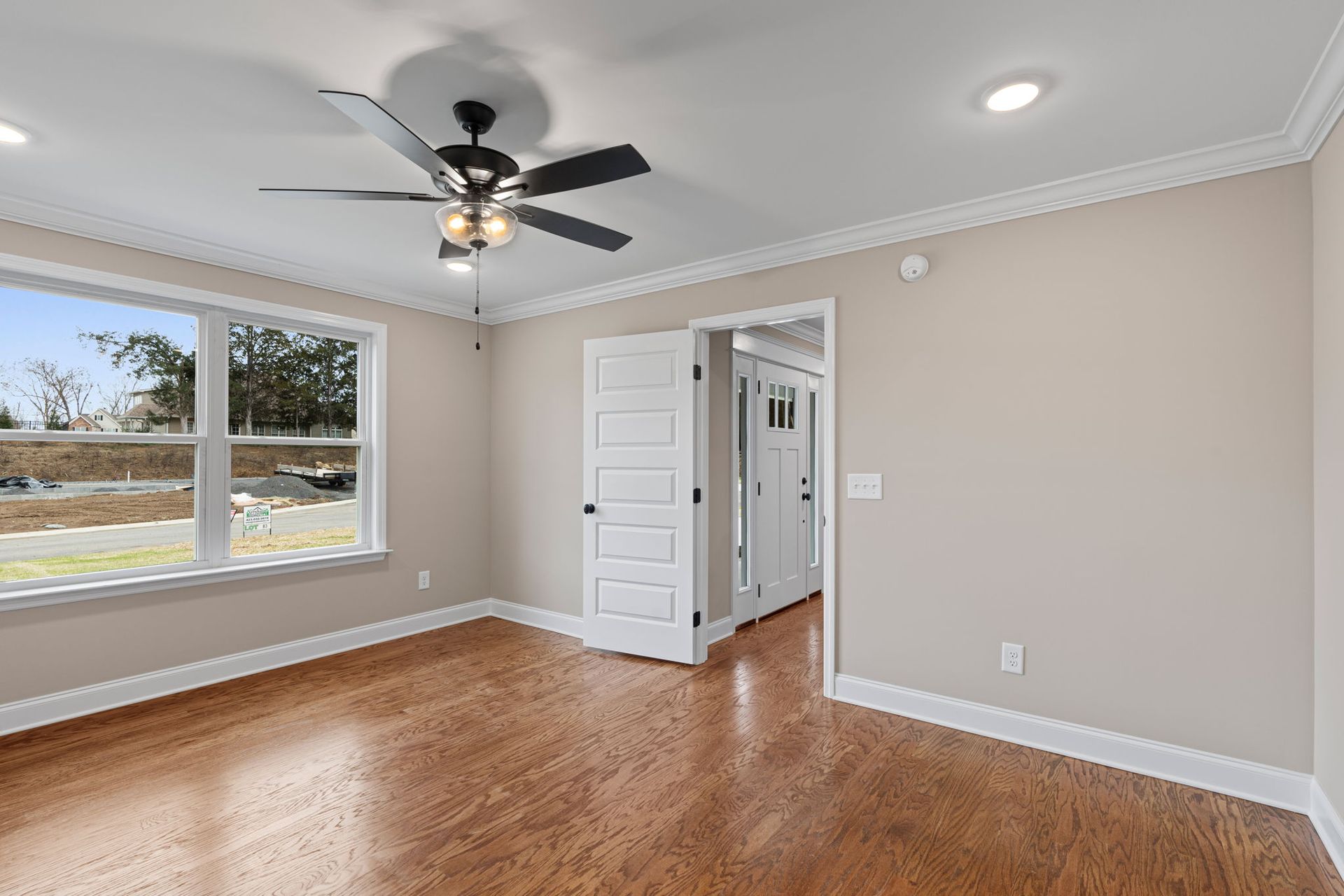 An empty room with hardwood floors and a ceiling fan.