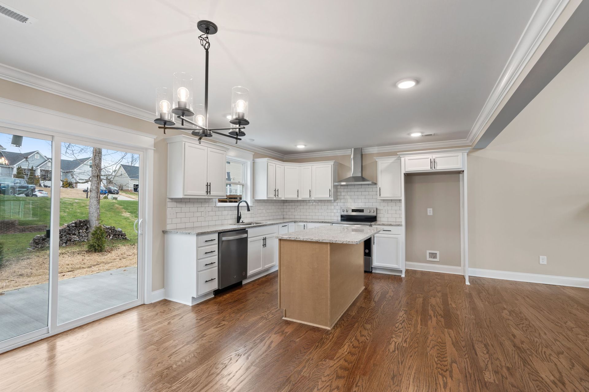 A kitchen with white cabinets , stainless steel appliances , hardwood floors and a large island.