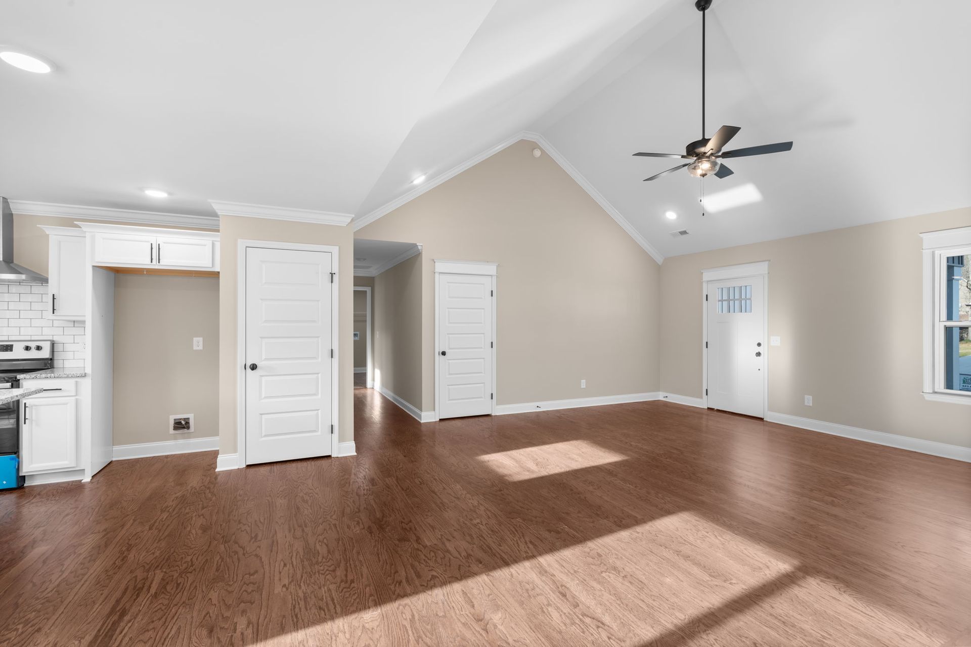 An empty living room with hardwood floors and a ceiling fan.