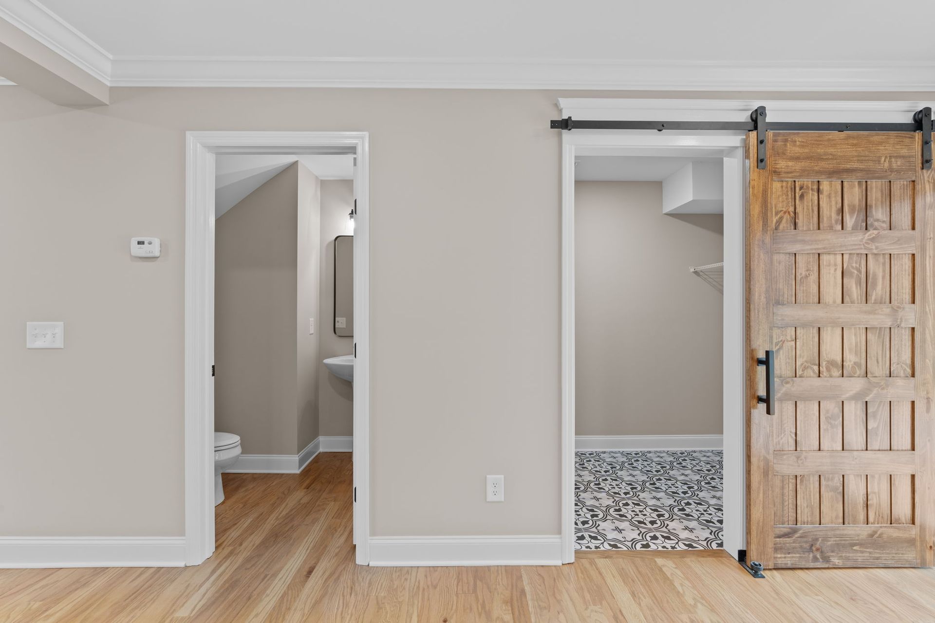 An empty room with a sliding barn door leading to a bathroom.