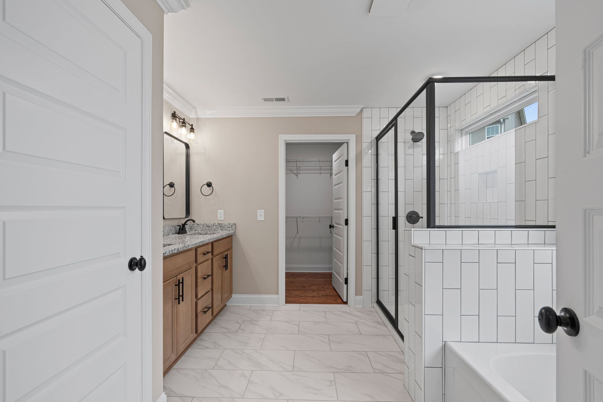 A bathroom with two sinks , a tub , and a walk in shower.