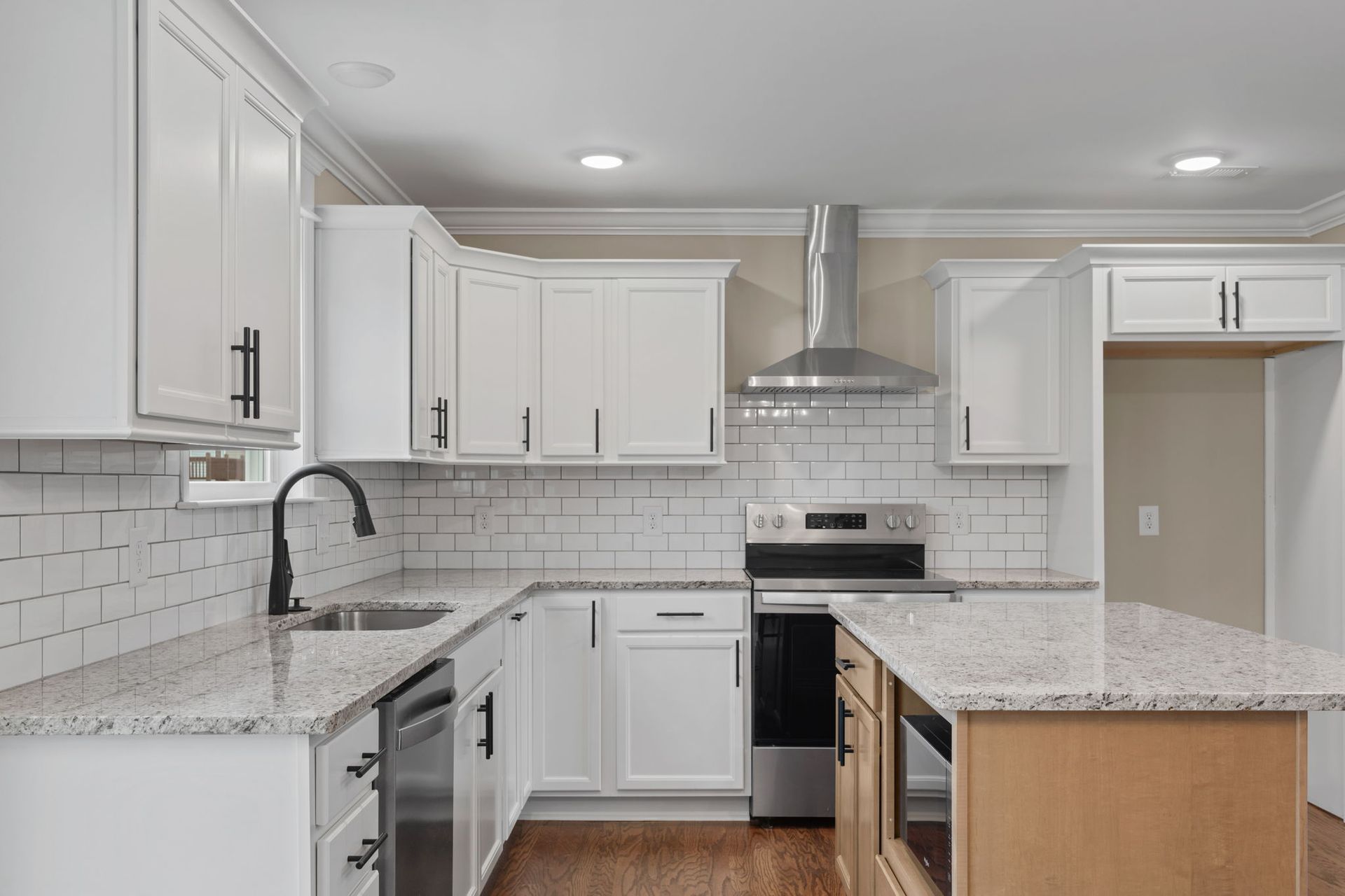 A kitchen with white cabinets , granite counter tops , stainless steel appliances and a large island.