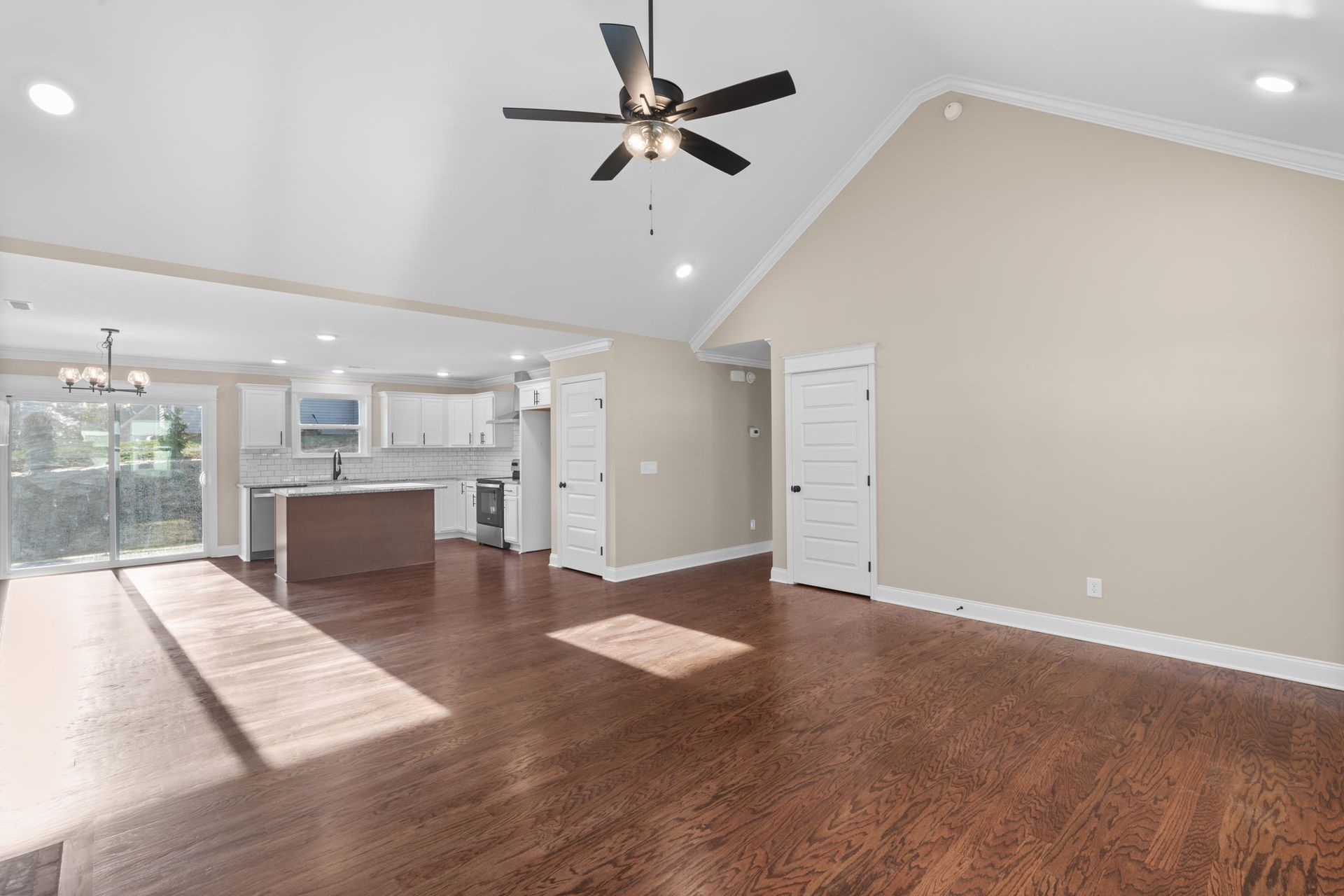 An empty living room with hardwood floors and a ceiling fan.
