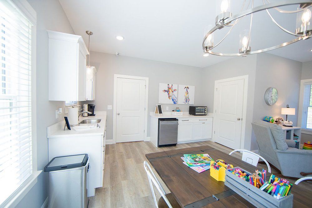 A room with a table , chairs , and a sink in it.