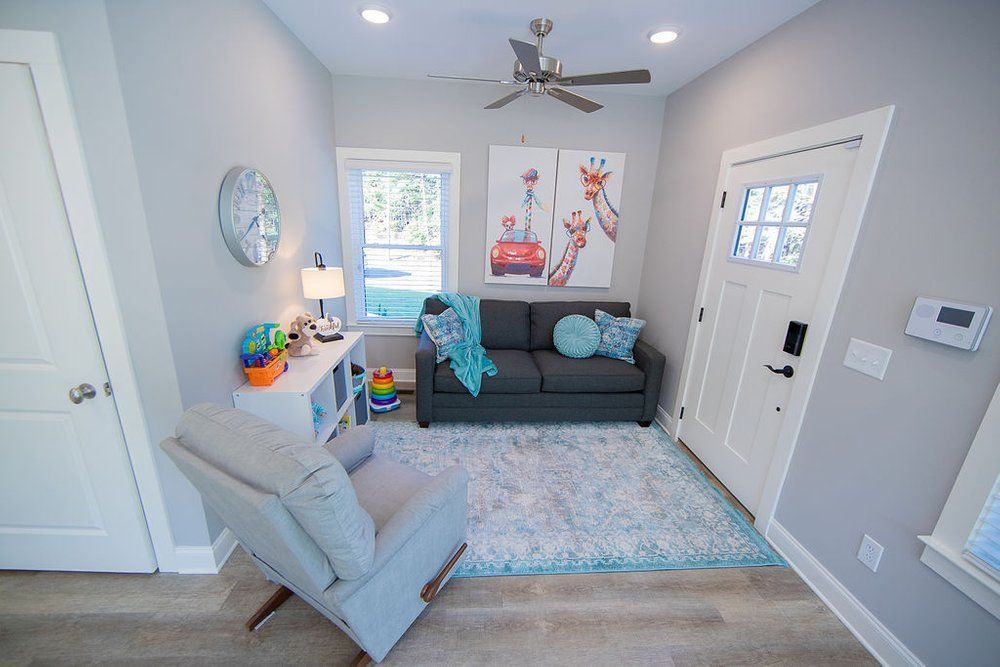 A living room with a couch , chair , and ceiling fan.