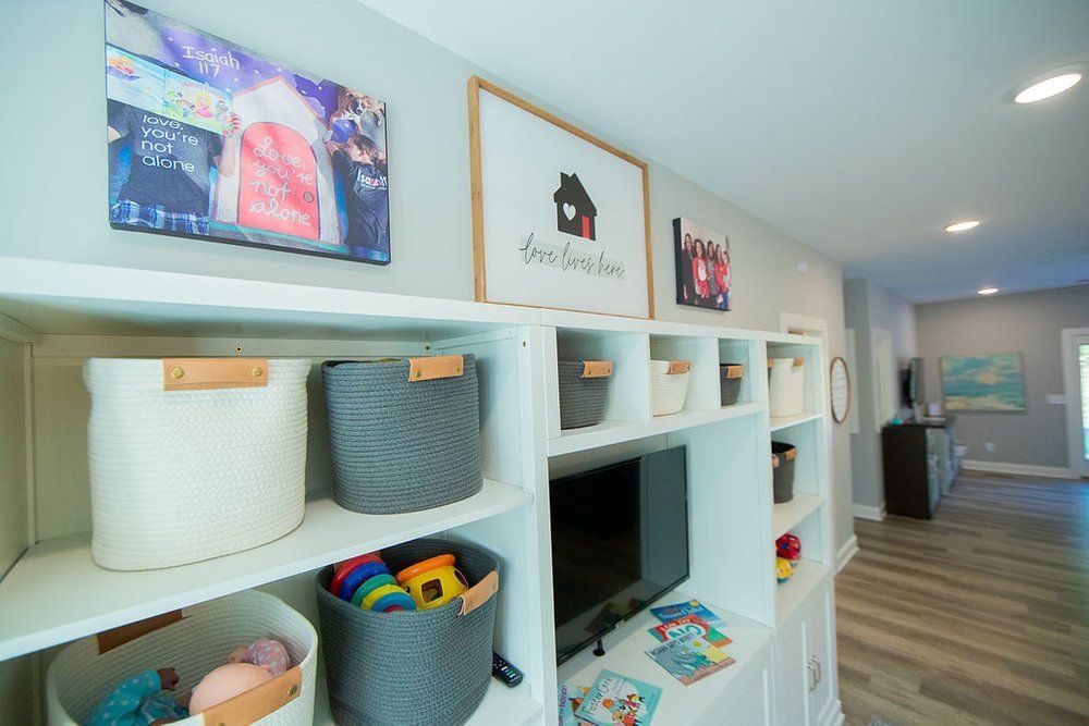 A living room with shelves filled with toys and a television.
