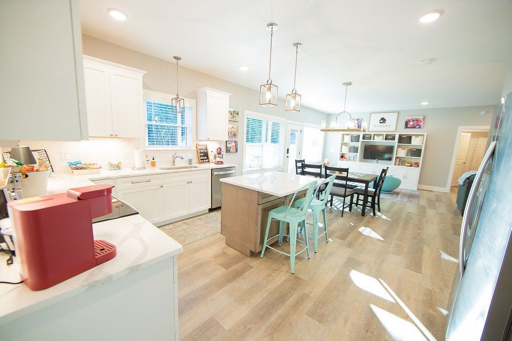 A kitchen and dining room in a house with a red coffee maker on the counter.