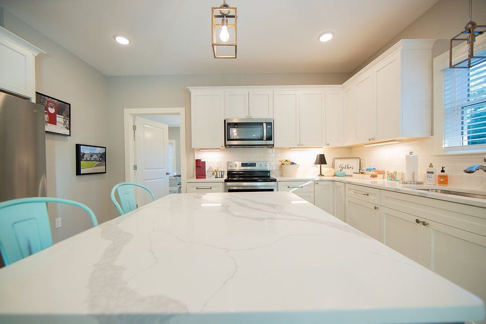 A kitchen with white cabinets , stainless steel appliances , and a large island.