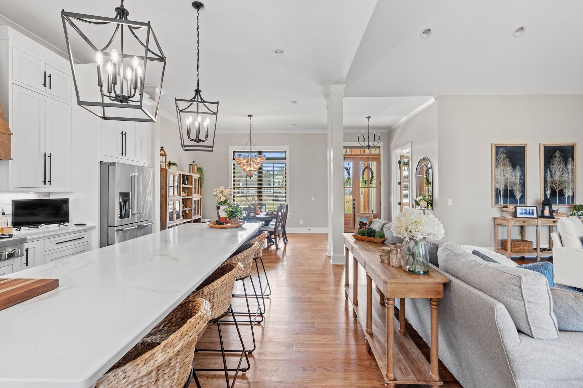 A kitchen and living room in a house with white cabinets and hardwood floors.