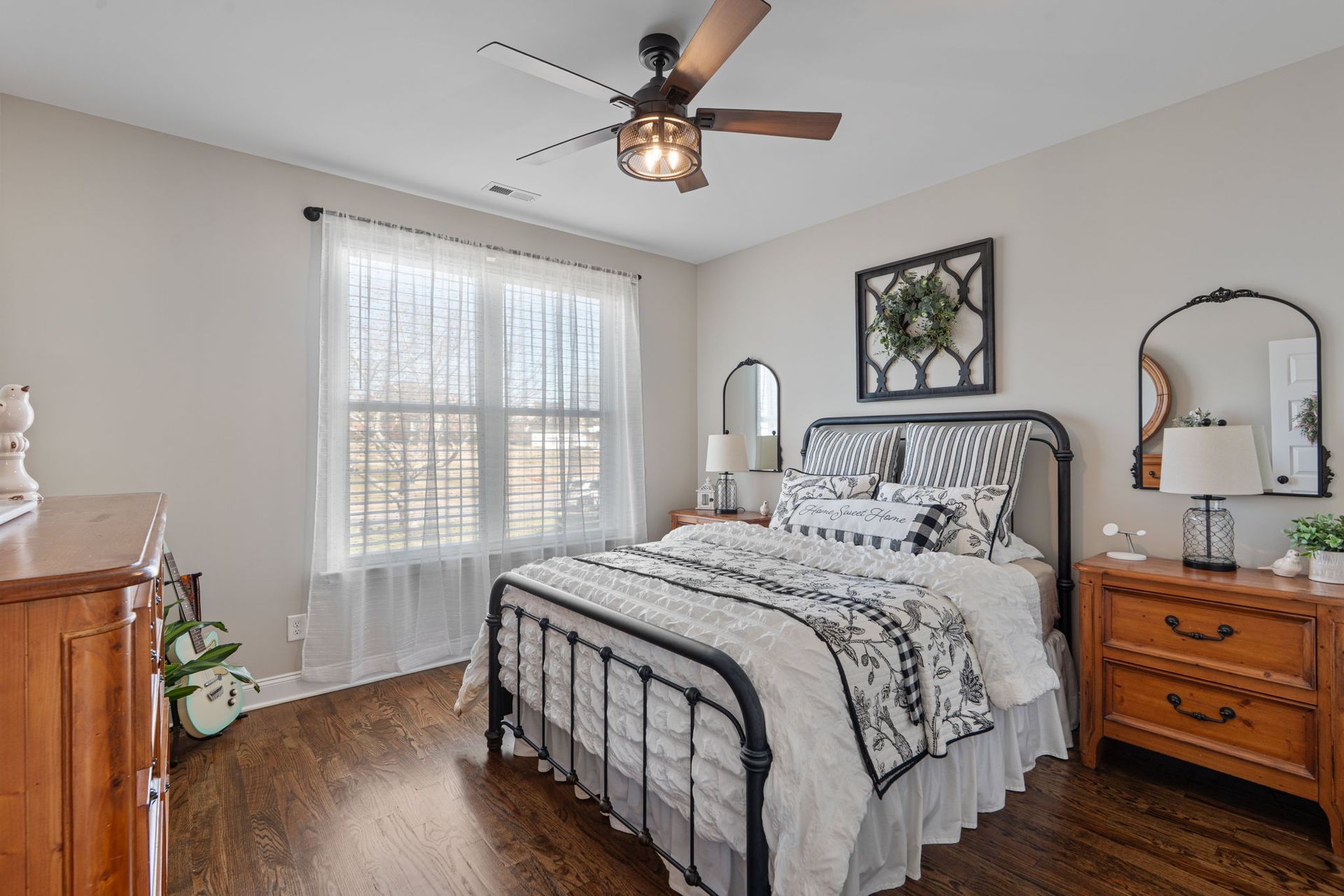 A bedroom with a bed , dresser , mirror and ceiling fan.