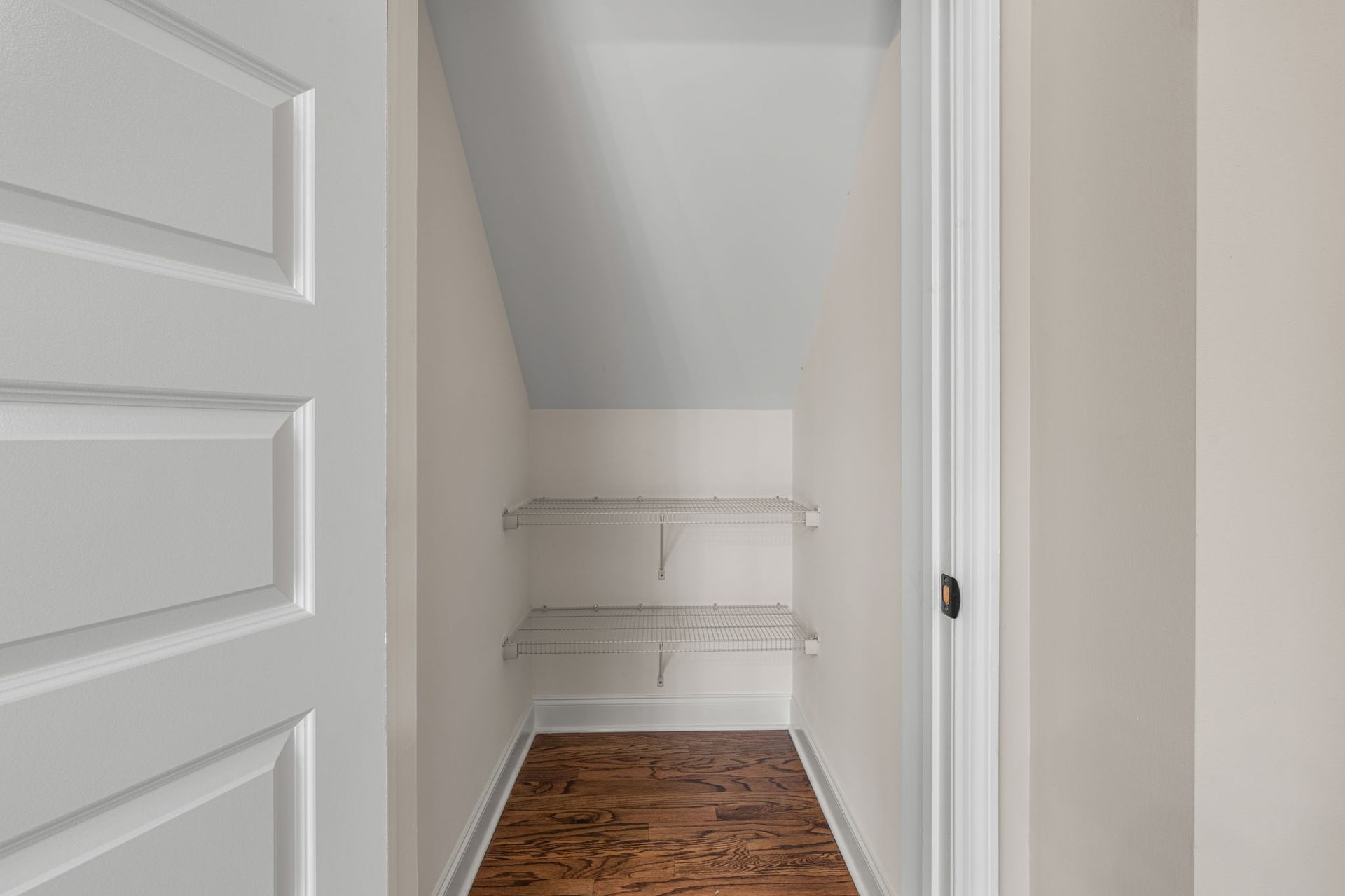 There is a closet under the stairs with a wooden floor.