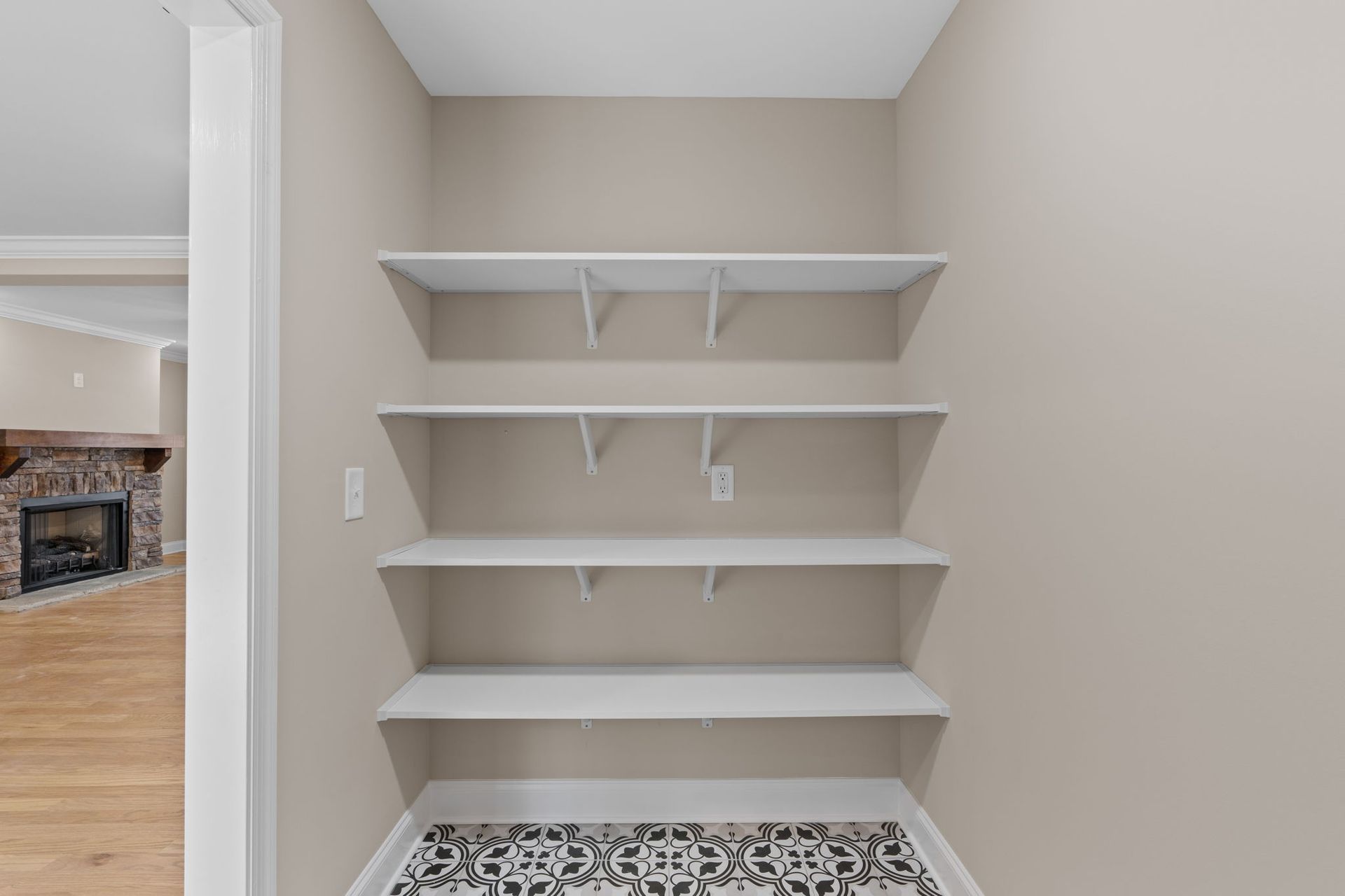 A closet with empty shelves and a fireplace in the background.
