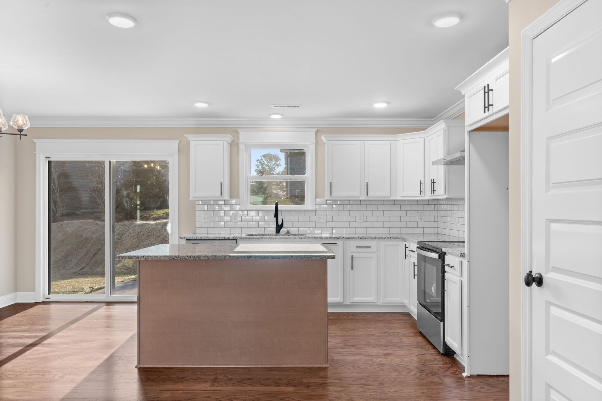 A kitchen with white cabinets and stainless steel appliances and a large island.