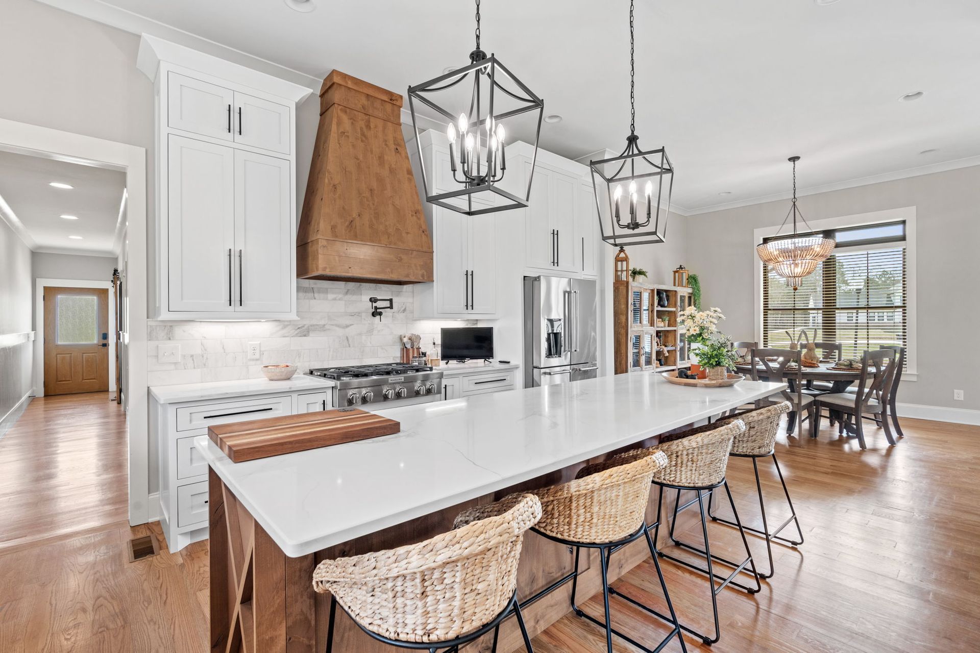 A kitchen with white cabinets , a large island , and wicker chairs.