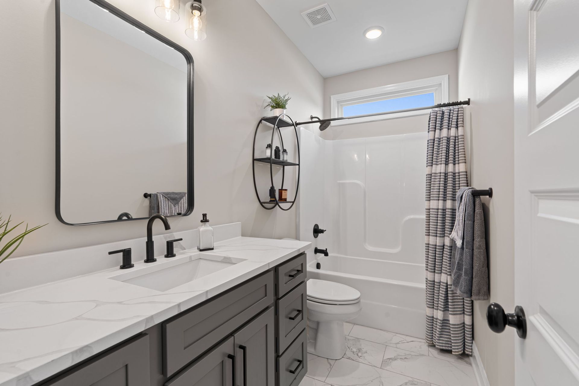 A bathroom with a sink , toilet , shower and mirror.