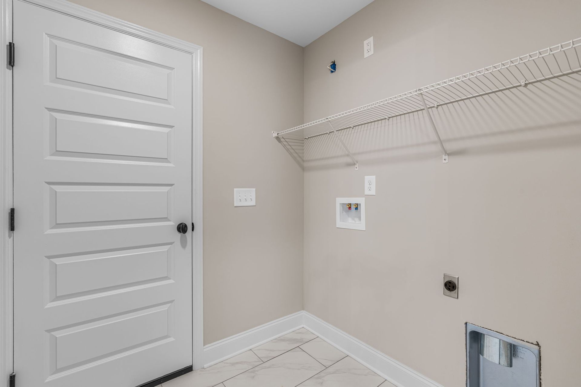 A laundry room in a house with a door and a shelf.