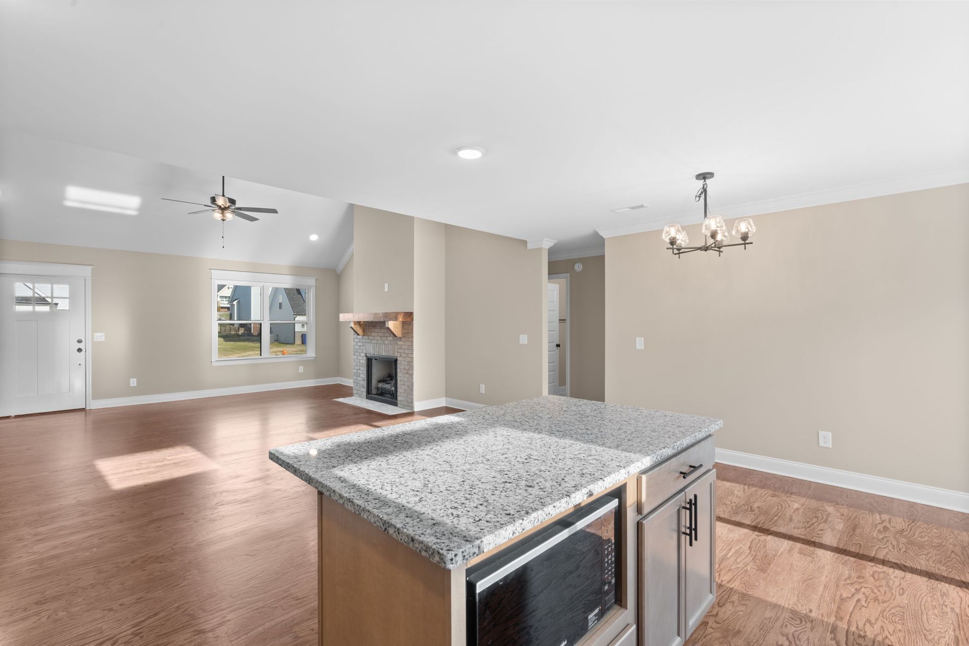 An empty kitchen with a granite counter top and stainless steel appliances.