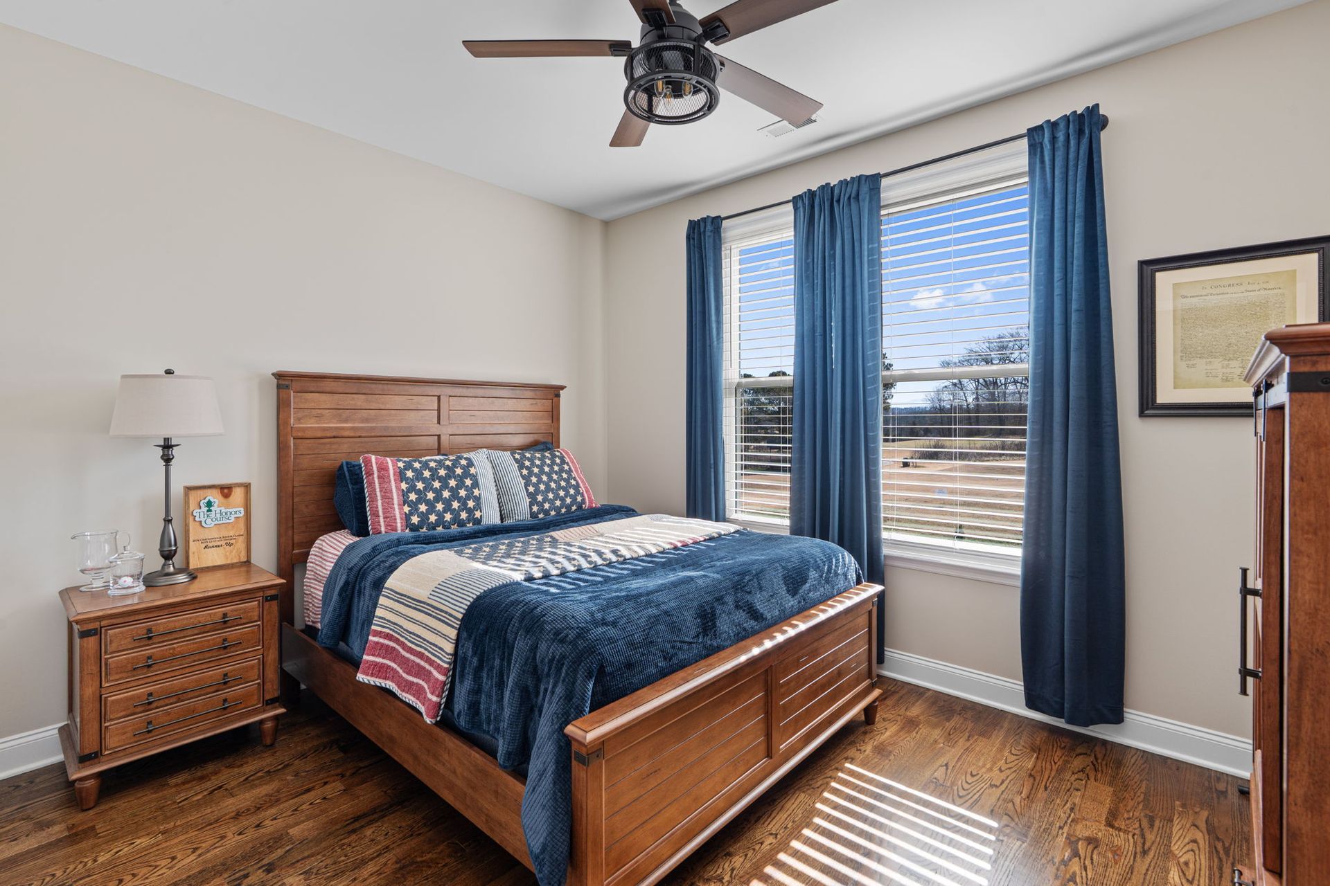 A bedroom with a bed , nightstand , dresser and ceiling fan.